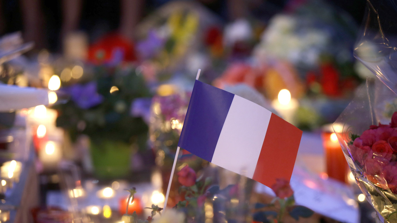 Drapeau français au milieu des fleurs et bougies d’un mémorial en hommage aux victimes de l’attentat de Nice, le 15 juillet 2016 à Nice (© AP Photo/Luca Bruno)(Bing France)