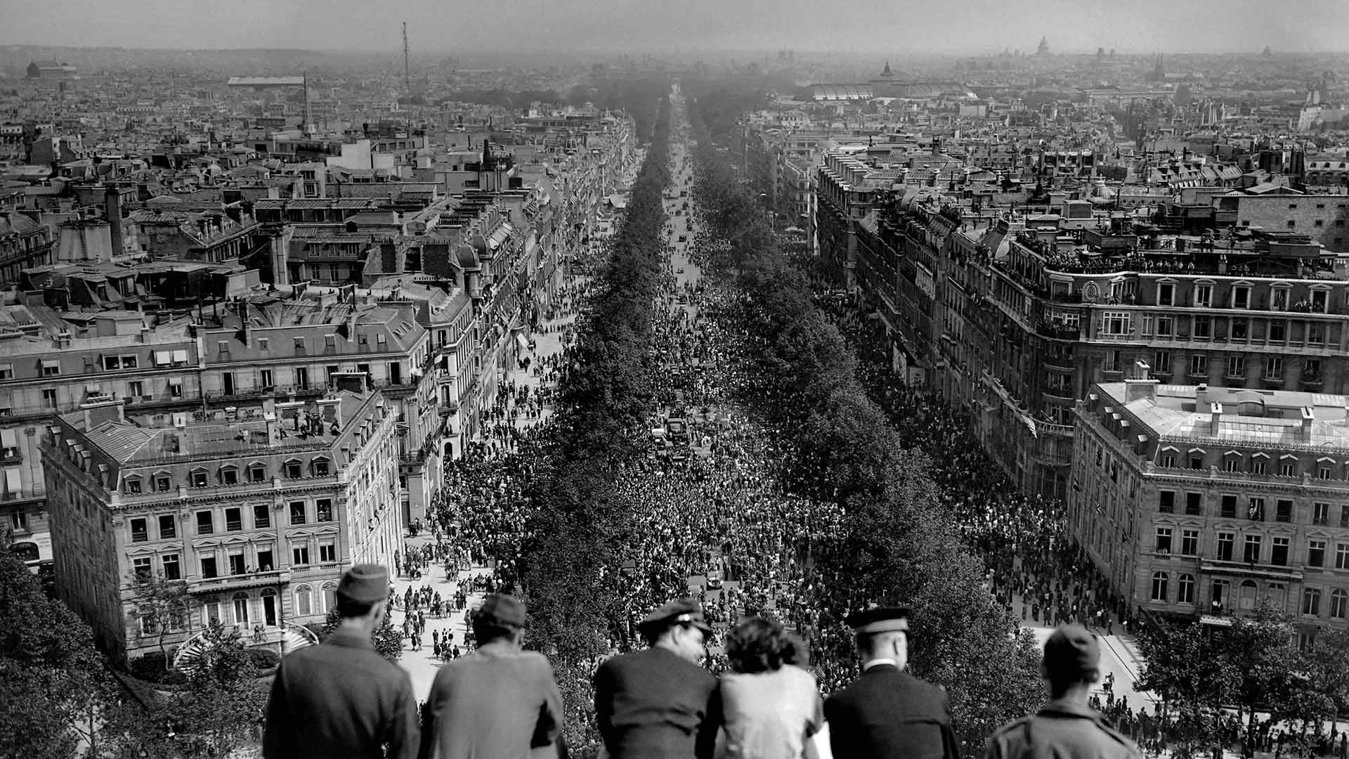 People looking at the crowded Avenue des Champs-Élysées from the Arc de Triomphe on May 8, 1945, Paris, France (© AFP via Getty Images)(Bing United States)