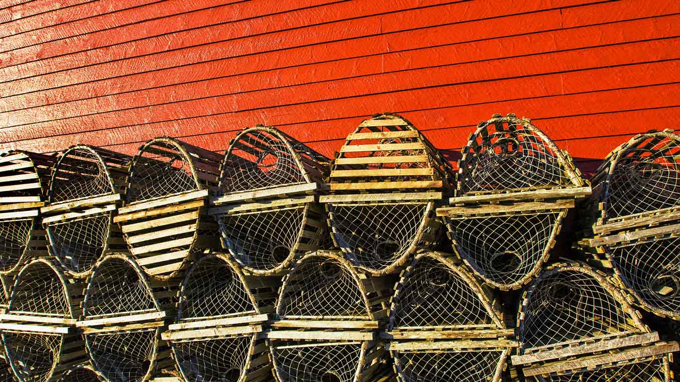 Lobster traps stacked against a red fishing shed in Newfoundland, Canada (© David Kleyn/Alamy)(Bing United Kingdom)
