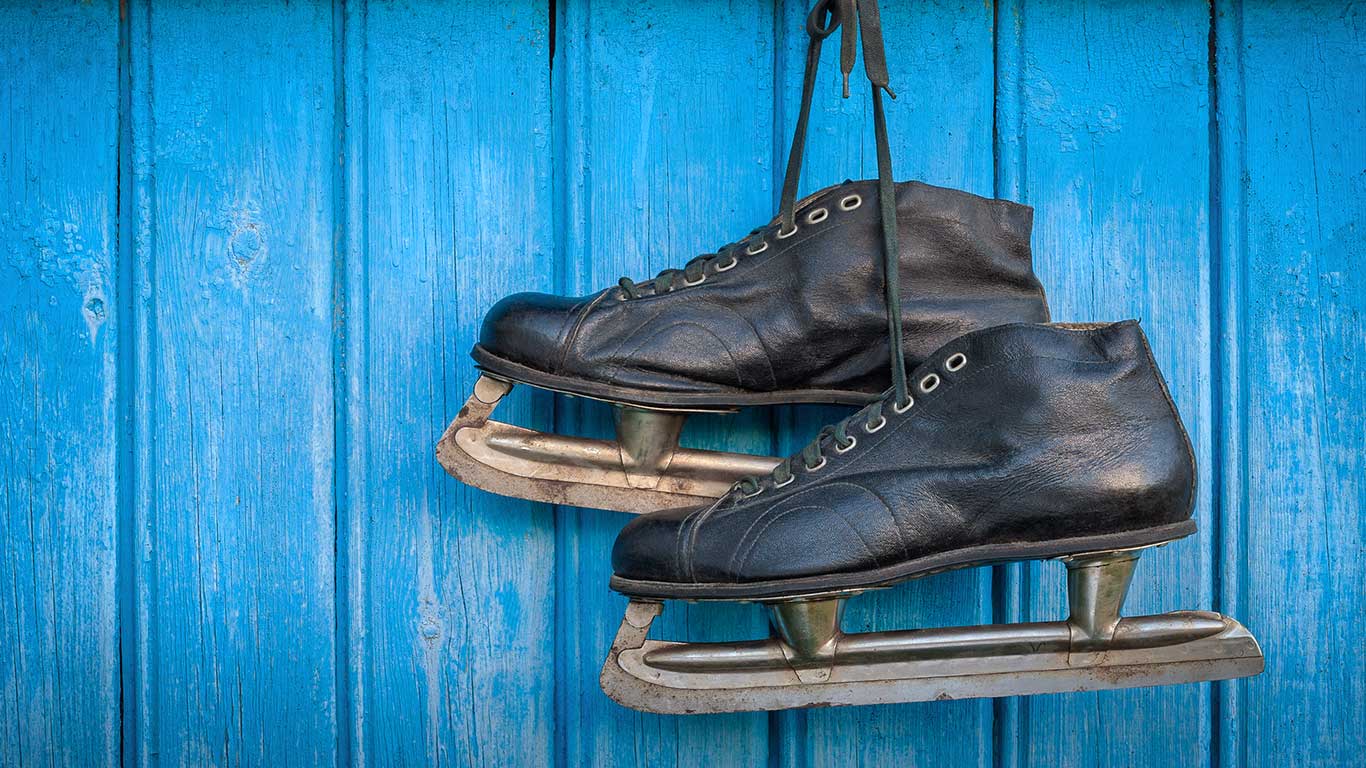 Old hockey skates hanging on a blue wooden wall (© SergeKa/Getty Images)(Bing Canada)