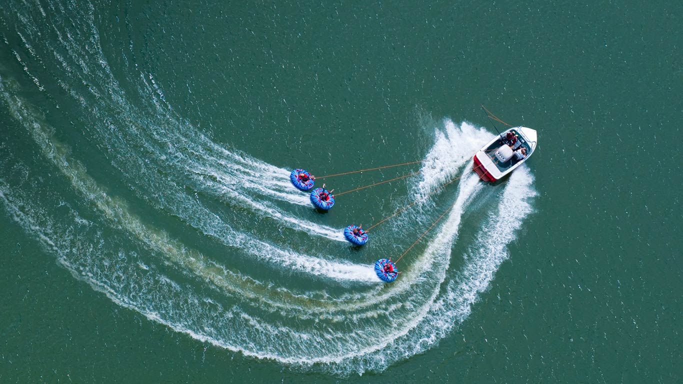 A speedboat tows four “tubers” on Abbey Lake in Surrey, England (© Jason Hawkes/Getty Images)(Bing Canada)