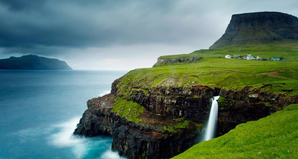Village of Gásadalur below Heinanova mountain, with waterfall cascading over cliff into the Atlantic Ocean, Faroe Islands (© Kimberley Coole/Lonely Planet) &copy; (Bing United Kingdom)